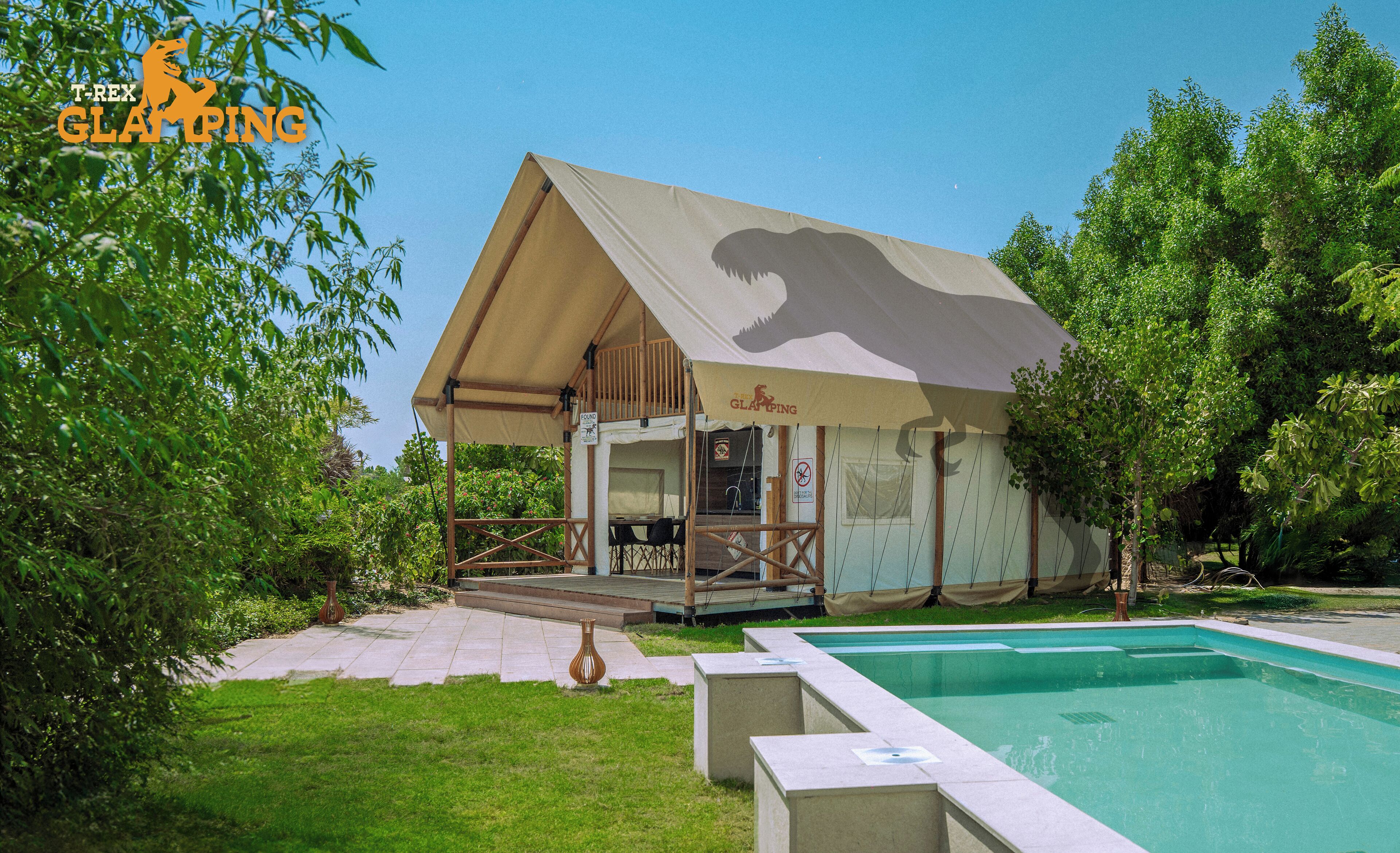 A glamping site with a tent structure, a pool, and surrounding greenery.