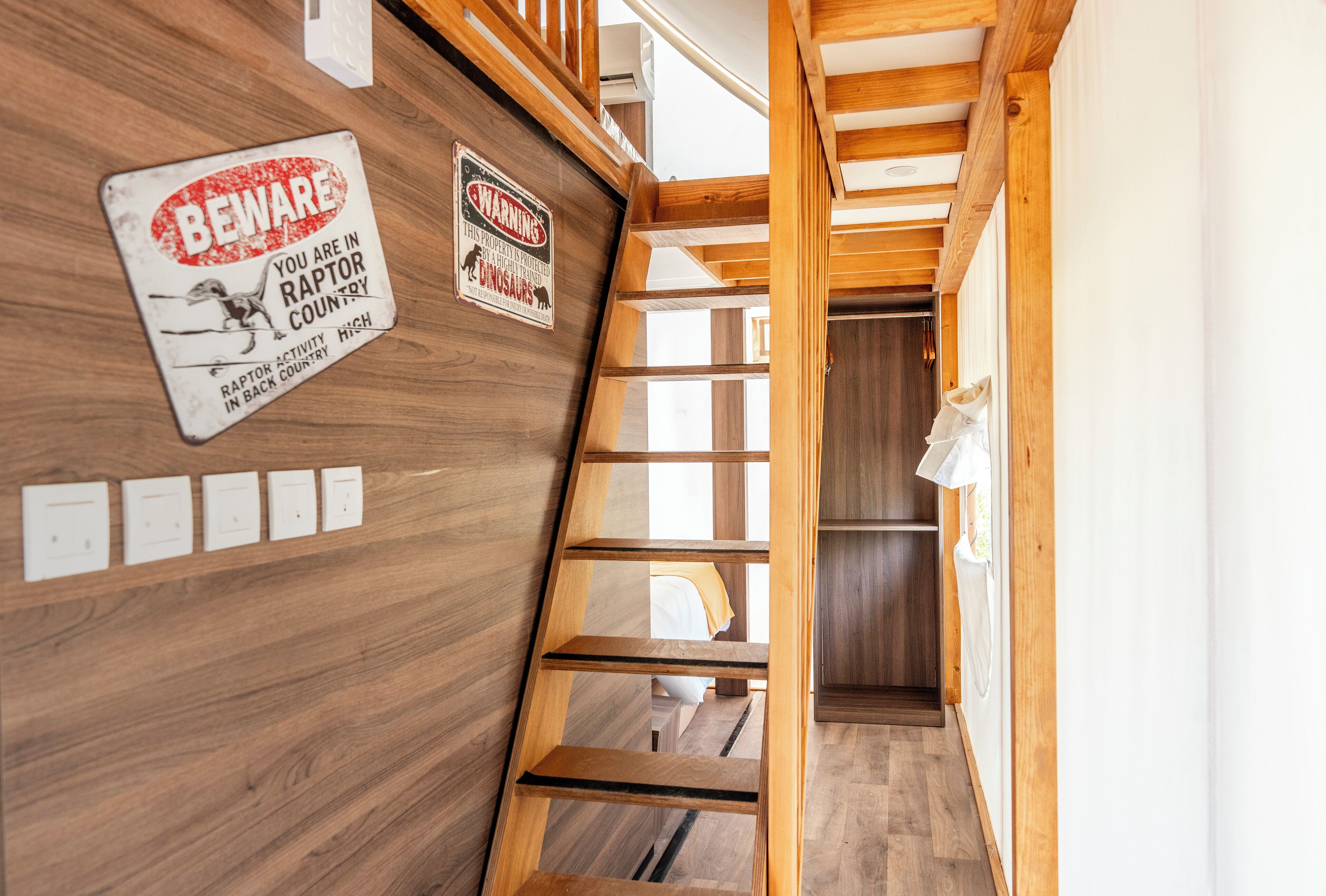 Un escalier en bois avec un panneau d’avertissement indiquant la présence de rapaces dans les environs.