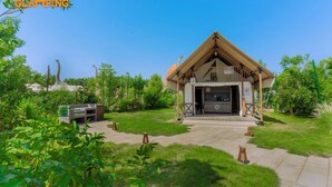 A wooden building with a sloped roof, a porch, and a sign indicating a restaurant. - T-Rex Glamping, Dubai Parks and Resorts (Dubai)