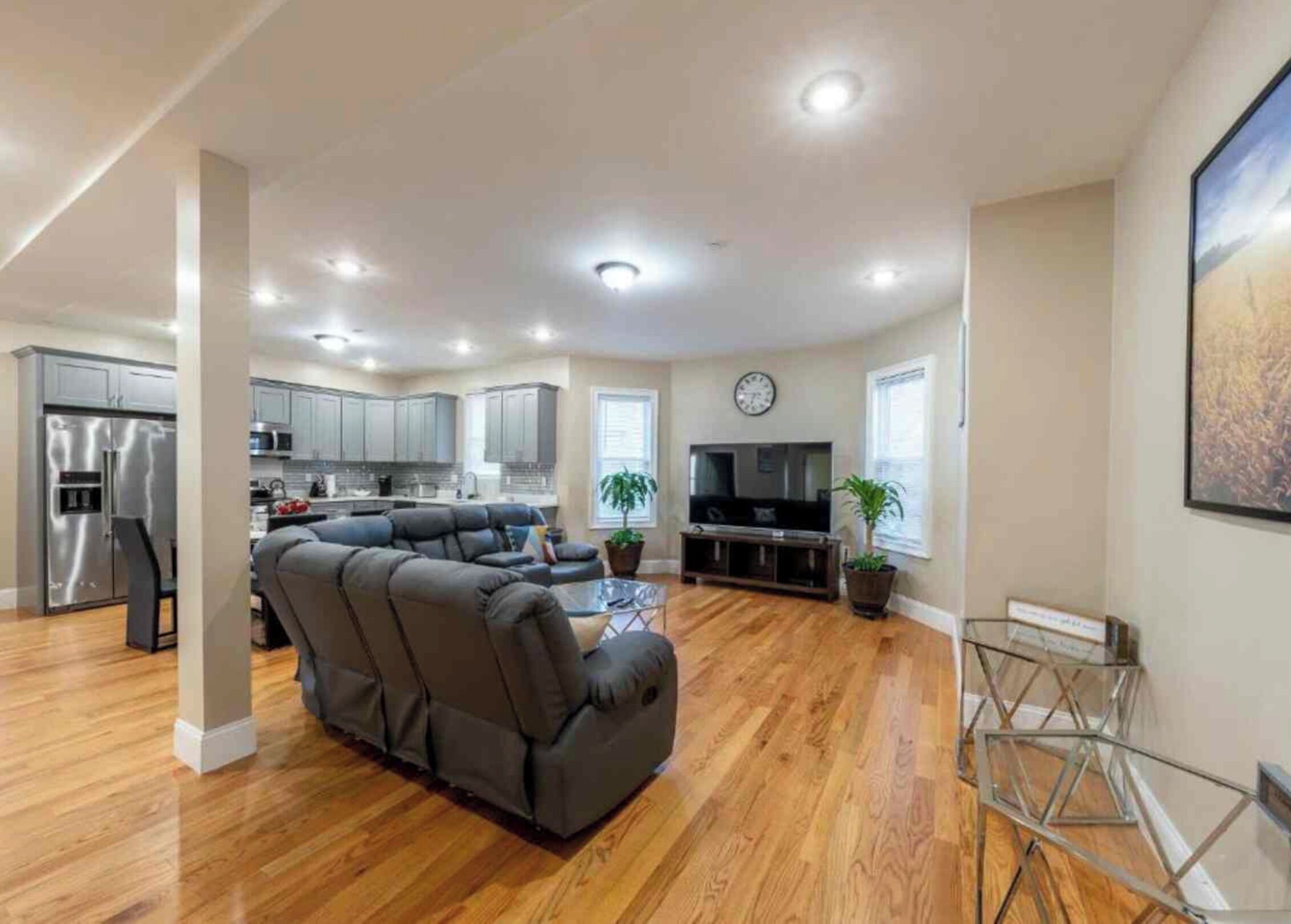 A modern living room with a sectional sofa, a flat-screen TV, and a dining area with a glass table.
