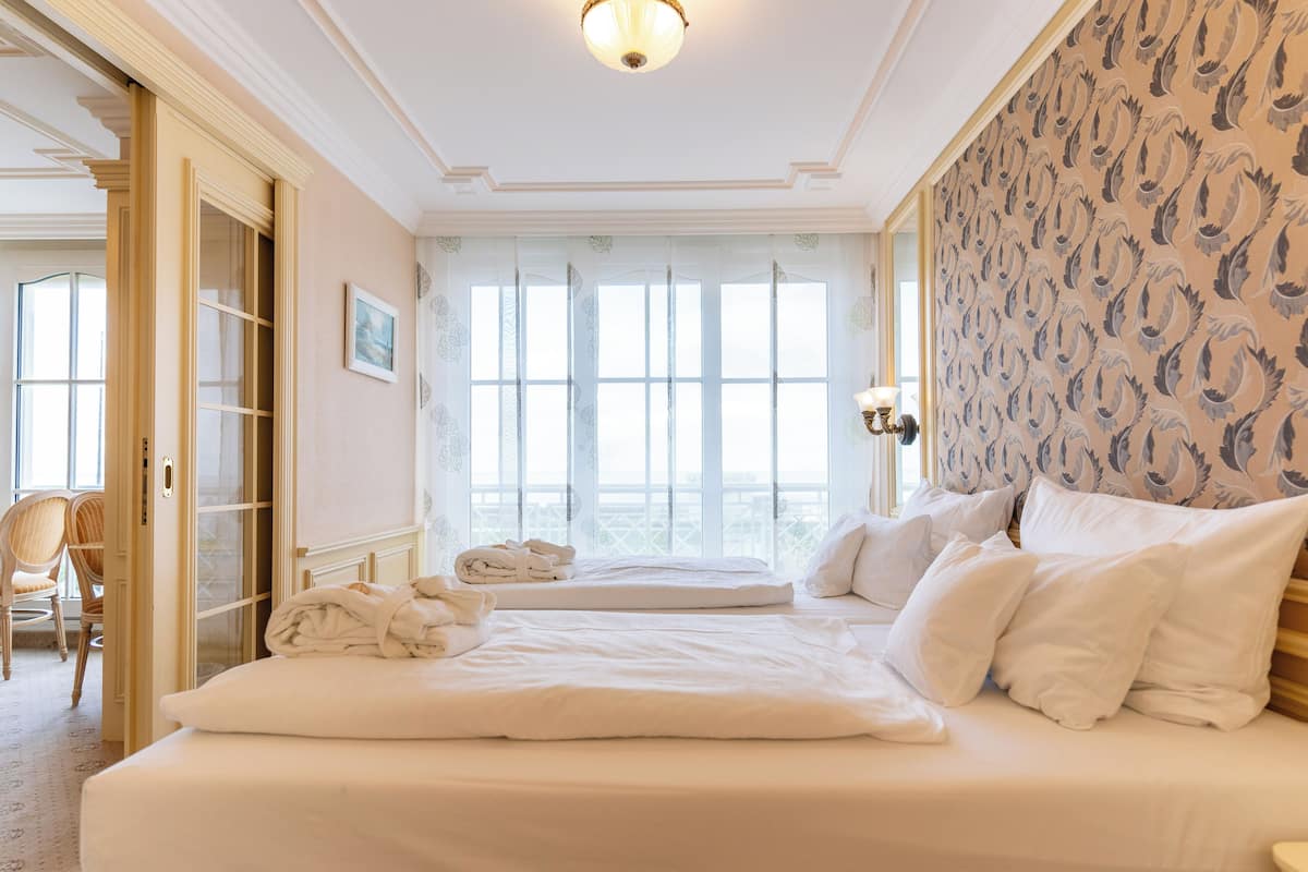 Ein Hotelzimmer mit einem großen Bett, einer Sitzecke mit einem Sessel und Blick aus dem Fenster.