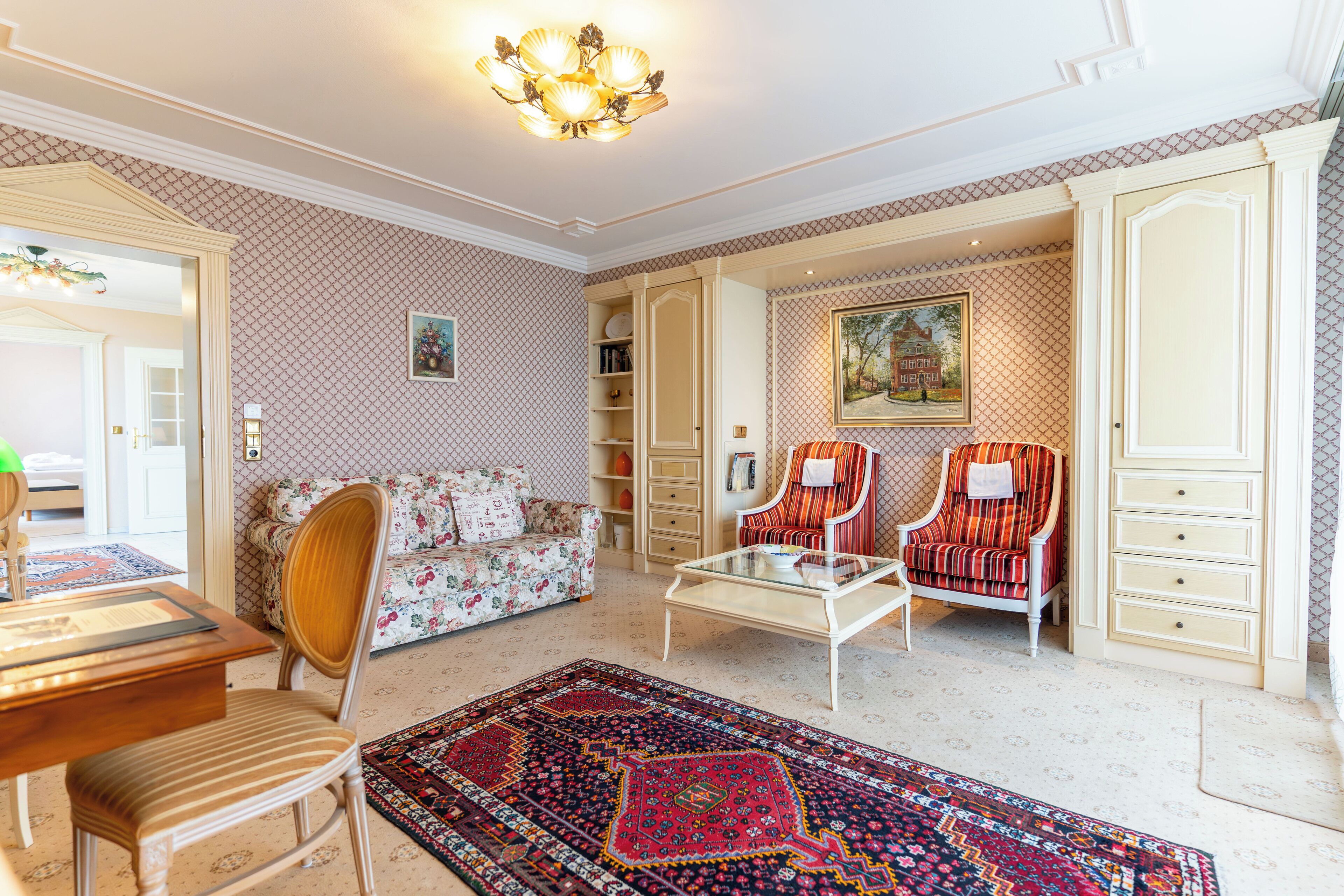 Un salón amplio con un sofá, dos sillones, una mesa de centro y una alfombra estampada.