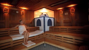 Uma sala de sauna com bancos de madeira, um espaço central para vapor e iluminação embutida nas paredes.