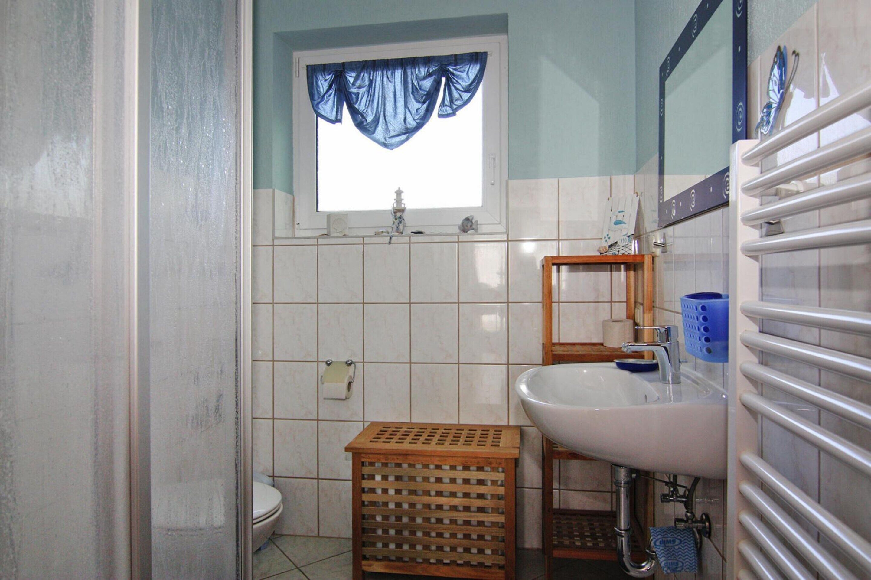 A bathroom with a toilet, sink, and window with blue curtains.