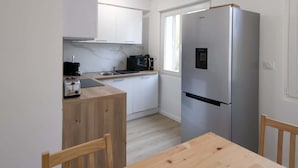 A compact kitchen with white cabinets, a stainless steel refrigerator, a microwave, and a toaster.