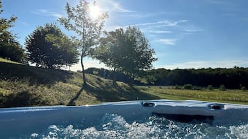 Een hottub omgeven door een grasrijk landschap met bomen en een heldere lucht.