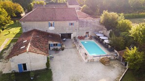 A large stone building with a swimming pool, outdoor seating, and a garden. - Le Patio Bleu (Saint-Romain)