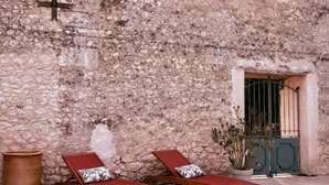 A stone building with two wooden lounge chairs and a large terracotta pot. - Le Patio Bleu (Saint-Romain)
