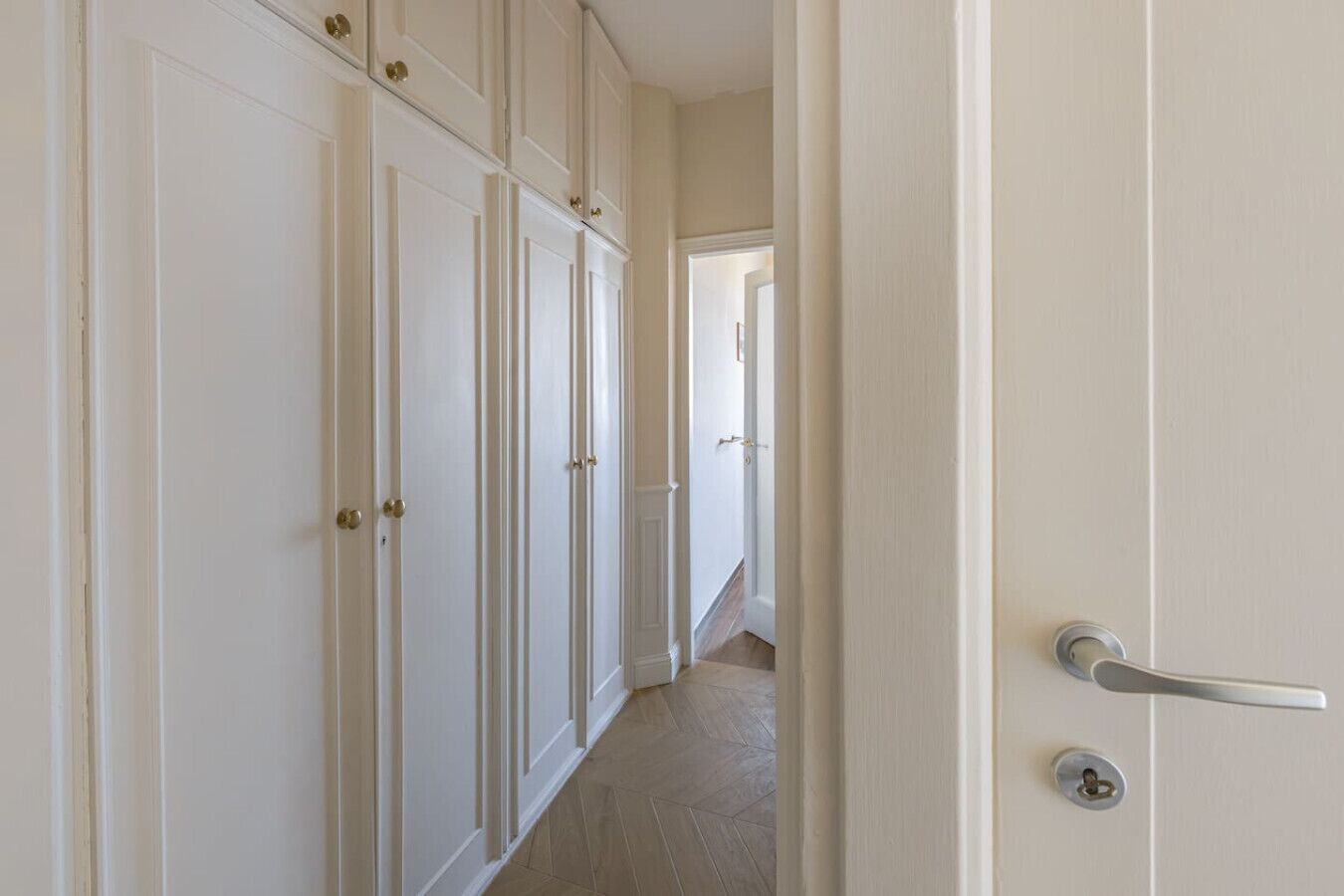 A hallway with white doors and a door handle.