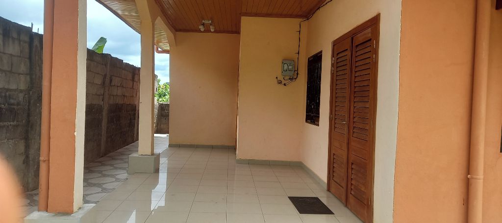 A corridor with tiled flooring, wooden doors, and a wall-mounted electrical box.