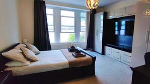 Een moderne hotelkamer met een groot bed, een televisie en een kledingkast.