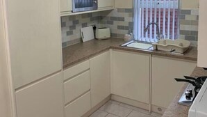 Een kleine keuken met een magnetron, broodrooster, spoelbak en kookplaat.