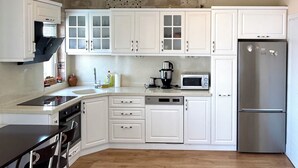 Eine moderne Küche mit weißen Schränken, einem Edelstahl-Kühlschrank, einer Mikrowelle und einem Geschirrspüler.