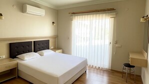 Ein Hotelzimmer mit einem großen Bett, einem Nachttisch, einem Sessel, einem Schreibtisch und einem Spiegel.