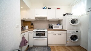 A compact kitchenette with a stove, microwave, coffee maker, and a washing machine. - Cute duplex studio, in the mountains, sleeps 5 (Allos)