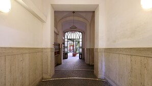 Un pasillo con suelo de baldosas, un amplio ventanal de arco y una lámpara colgante.