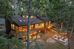 A two-story cabin with a deck, large windows, and a fire pit area.