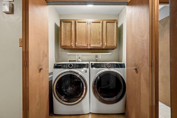 A laundry room with two front-loading washing machines and wooden cabinets above.