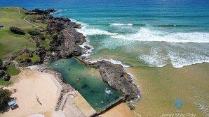 Une zone côtière comprenant une plage, des affleurements rocheux et des eaux cristallines.