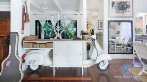 Une pièce décorée avec un scooter blanc d’époque, une guitare et une fresque murale.