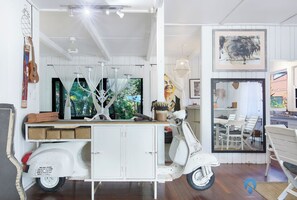 Une pièce décorée avec un scooter blanc d’époque, une guitare et une fresque murale.