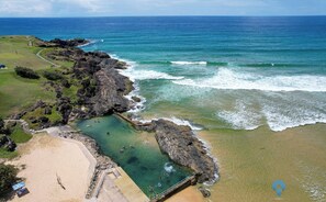 Une zone côtière comprenant une plage, des affleurements rocheux et des eaux cristallines.