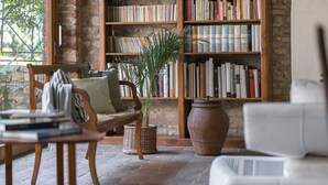 Een knus hoekje om te lezen, met een houten bankje, een witte fauteuil en een boekenplank vol boeken.