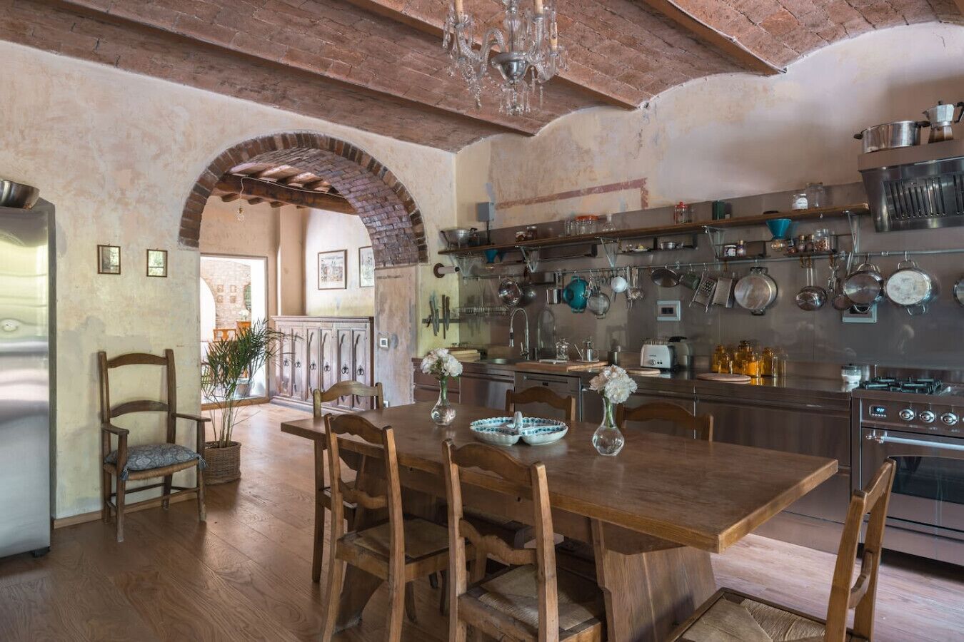 Une cuisine rustique avec des meubles en bois, une arche en briques et divers ustensiles de cuisine accrochés au mur.