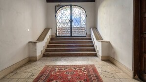 A staircase with a patterned rug at the bottom, leading to a door with a metal gate. - Lim1939 apartment in Florence (Firenze)