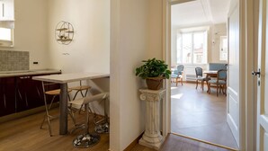 A modern kitchen with a bar area, a dining table with chairs, and a potted plant. - Lim1939 apartment in Florence (Firenze)