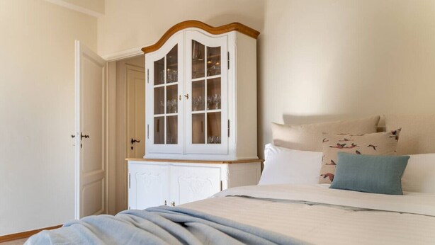 A bedroom with a bed, a white wardrobe with glass doors, and a door to another room. - Lim1939 apartment in Florence (Firenze)