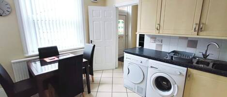 A compact kitchen with a dining area, a washing machine, and a sink.