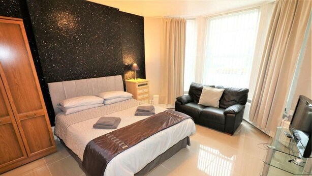 Ein Schlafzimmer mit einem Bett, einem Schlafsofa, einem Fernseher und einem Kleiderschrank.