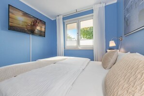 A bedroom with a bed, a window with white curtains, a painting on the wall, and a nightstand with a lamp. - Modern apartment with terrace and comfort in Ückeritz near the Baltic Sea beach (Ückeritz)