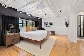 Un dormitorio con cama, mesita de noche, lámpara, ventana y puerta.