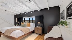 A modern bedroom with a large bed, bedside tables, a window with curtains, and a view of the outdoors.