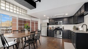 A modern kitchen with a dining area, large windows, and a view of the city.