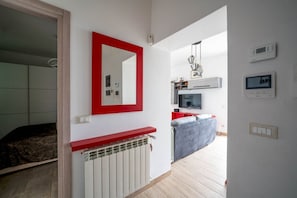 A modern apartment with a red-framed mirror, a radiator, a television, and a red cabinet.