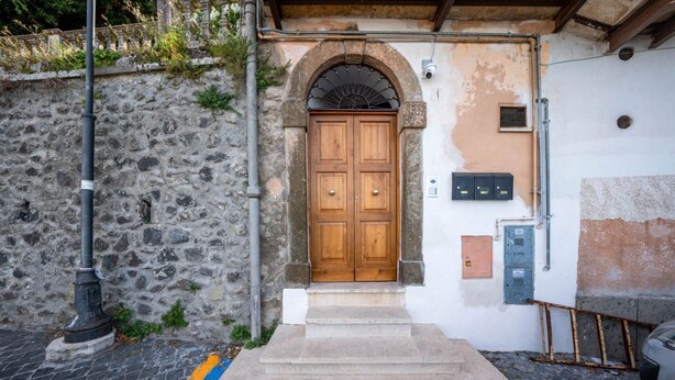 A stone wall with a wooden door, a metal pole, and a staircase leading to a door. - Al Belvedere A – Panoramic apartment in the Castelli Romani (Rocca di Papa) (Rocca di Papa)