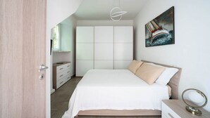 A bedroom with a bed, a dresser, a bedside table, a painting, and a ceiling light fixture. - Al Belvedere A – Panoramic apartment in the Castelli Romani (Rocca di Papa) (Rocca di Papa)