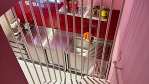 A modern kitchen with red tiles, stainless steel appliances, and a view through a barred window. - Casetta della Morica alle Gole Del Nera (Stifone)
