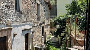 A stone building with a balcony, a small garden, and a view of a hillside. - Casetta della Morica alle Gole Del Nera (Stifone)