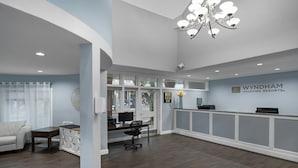 A reception area with a desk, computer, and a chandelier.