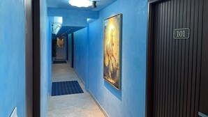 A hallway with blue walls, a ceiling light, a door labeled '101', and a large painting of a horse. - Cool hotel with AC in vibrant Kozhikode (Kozhikode)