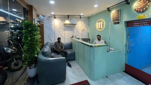 A reception area with a marble wall, a reception desk, and a seating area with a potted plant. - Cool hotel with AC in vibrant Kozhikode (Kozhikode)
