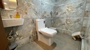 A bathroom with a toilet, sink, and shower. - Cool hotel with AC in vibrant Kozhikode (Kozhikode)