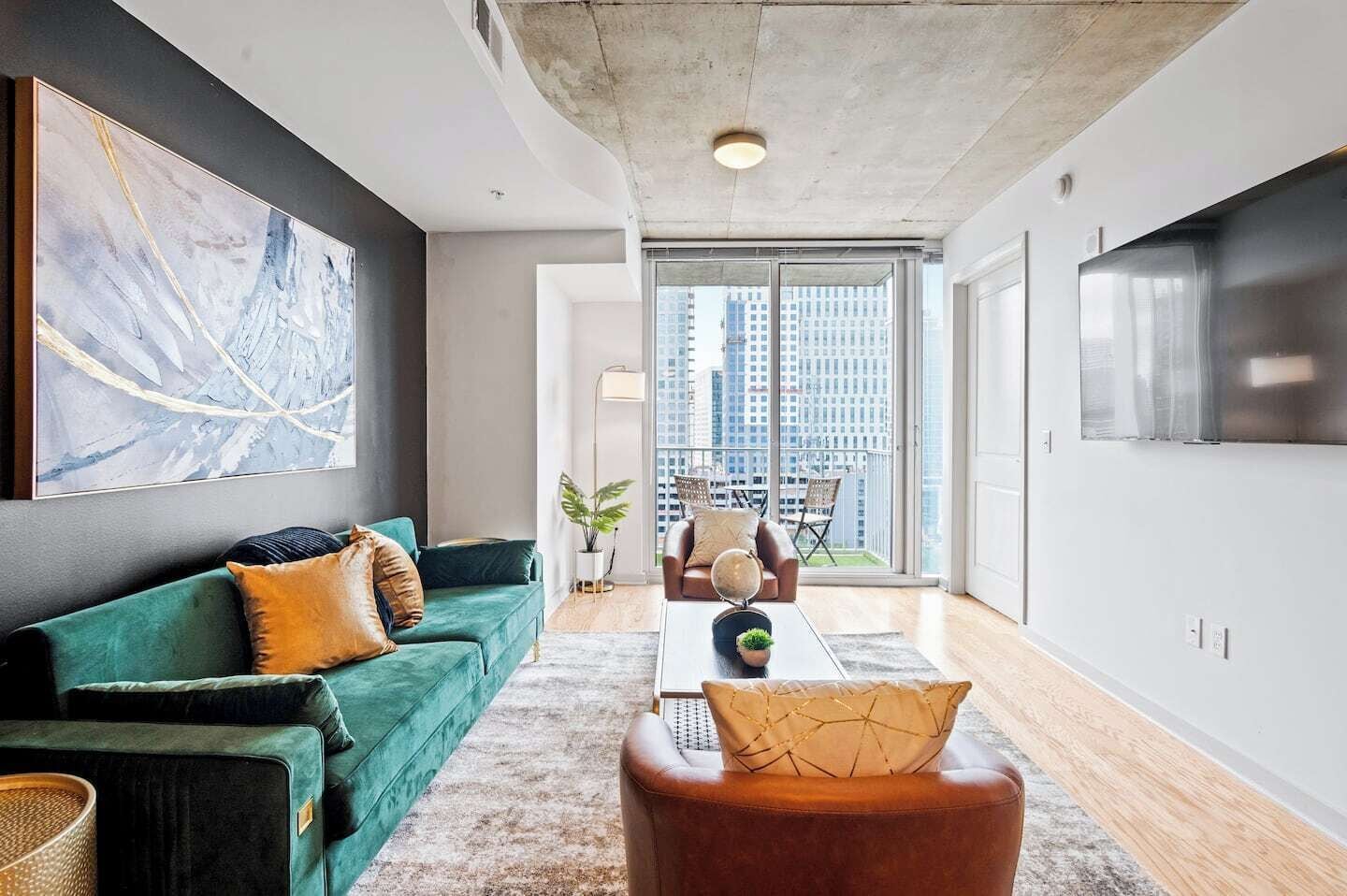 A modern living room with a green sofa, a coffee table, and a large abstract painting on the wall.