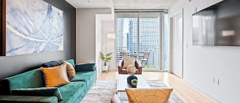 A modern living room with a green sofa, a coffee table, and a large abstract painting on the wall.