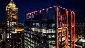 A modern building with a prominent Google sign, featuring a glass facade and a red structural framework.