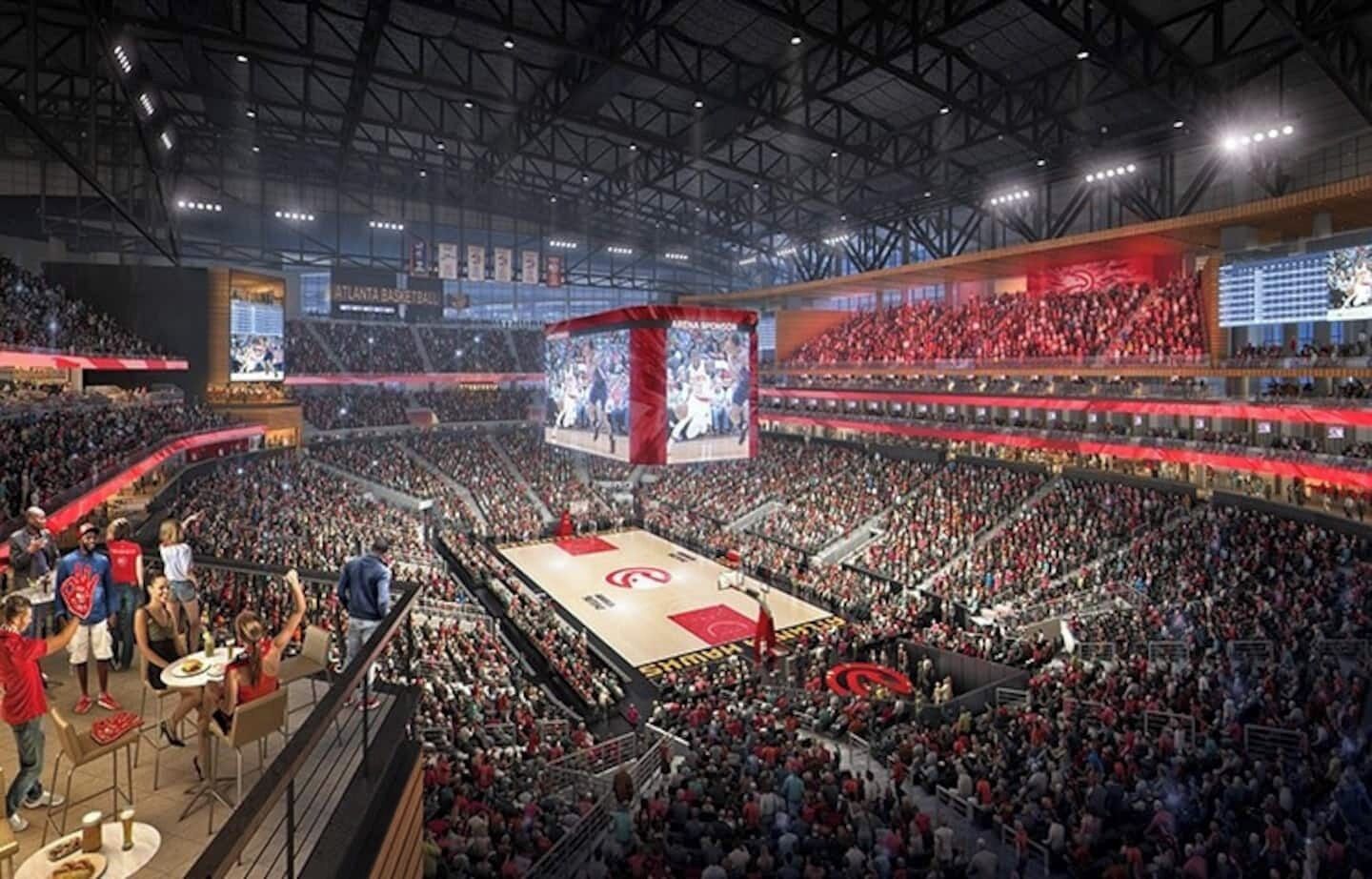 A large indoor sports arena with a basketball court, seating for spectators, and a large screen displaying an event.